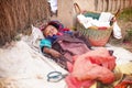 Tsiafahy, Madagascar - April 25, 2019: Unknown small Malagasy baby sleeping outside on the ground with straw and bags, covered