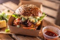 TTasty homemade burger takeaway in a box of recycled paper on wooden boards Royalty Free Stock Photo