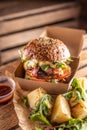 TTasty homemade burger takeaway in a box of recycled paper on wooden boards Royalty Free Stock Photo