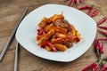 Tteok-bokki - traditional dish of korean cuisine, stir-fried rice cakes with pork ribs in white plate on wooden background. Close Royalty Free Stock Photo