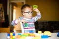 Little boy with syndrome dawn in the black glasses playing with blocks