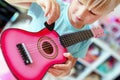 Little cute blond girl having fun learning to play small ukulele guitar at home.Toddler girl trying to play toy musical instrument Royalty Free Stock Photo