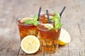 Ttree glasses of traditional iced tea with lemon, mint leaves and ice cubes on rustic wooden table