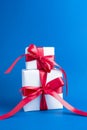 Two white boxes tied with a red satin ribbon bow on a classic blue background. Gifts for the holiday. Valentine`s day. Royalty Free Stock Photo