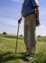 Tubby old man with walking stick in the countryside with grass and a blue sky in the background Royalty Free Stock Photo