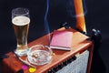 Tube amplifier for guitar with black guitar, glass of beer and smoking cigarette on black background