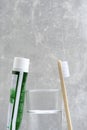 Tube toothpaste, brush and glass water gray background in bathroom.