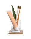 Tube of toothpaste, brushes and aloe vera leaf in glass on white background