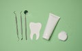 Tube with toothpaste, dental floss and medical mirror on a green background, oral hygiene