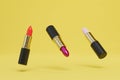 tubes of lipstick of different colors flying on a yellow background. 3D render Royalty Free Stock Photo