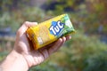 Tuc snack pack in male hand on a green trees background