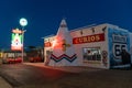 Tepee Curios gift shop and neon sign, a famous classic Route 66 landmark, at night