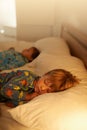 Tuckered out after a day full of fun. two little boys sleeping on a bed with the light on.