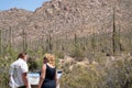 Two tourists wearing face masks read a storyboard for additional information at Saguaro National