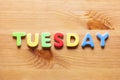 Tuesday word written with colorful letters on wooden table background
