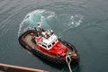 A tug boat drags the boat dock lines from a cruise ship to the dock to be tied up Royalty Free Stock Photo