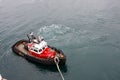 A tug boat drags the boat dock lines from a cruise ship to the dock to be tied up. tug boat drags the boat dock lines from a Royalty Free Stock Photo