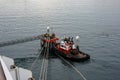 A tug boat drags the boat dock lines from a cruise ship to the dock to be tied up Royalty Free Stock Photo