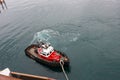 A tug boat drags the boat dock lines from a cruise ship to the dock to be tied up Royalty Free Stock Photo