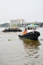 Tug boat drags sand barge on Chao Phraya river, Bangkok