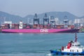 Tug boat sailing on the background of the large pink container ship