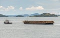 Tug boat tows bulk cargo lighter barge along Singapore strait near Indonesia shore with small islands in the background Royalty Free Stock Photo