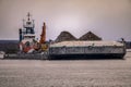 Tug pushing a barge in the river with iron pellets