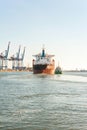 Tugboat assisting bulk cargo ship in a harbor. Front view. Royalty Free Stock Photo