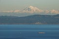 A tugboat and barge travel through the Salish Sea with the beautiful Mount Baker of Washington State in the background Royalty Free Stock Photo