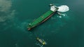 tugboat dragging cargo ship leaving shipyard after repairs in green sea, aerial top view Royalty Free Stock Photo