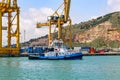 Tugboat in the port of Barcelona with large container unloading