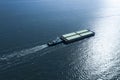 Tugboat pulling barge with cargo by water, aerial view