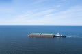 Tugboat pulling barge with cargo by water, aerial view