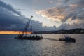 Tugboat pulls a crane-barge up beside the coastline Royalty Free Stock Photo