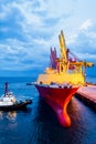 Tugboat push large cargo vessel to berth at port terminal. Port terminal operations and handling equipment