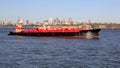 Tugboat pushing a barge RTC 82 across New York harbor, waterfront of the Brooklyn Heights in the background