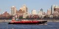 Tugboat pushing a barge RTC 82 across New York harbor, waterfront of the Brooklyn Heights in the background