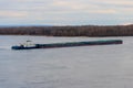 Tugboat pushing heavy long barge on the river Dnieper