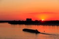 Tugboat pushing heavy long barge on the river Dnieper at sunset