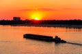 Tugboat pushing heavy long barge on the river Dnieper at sunset