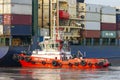 Tugboat Pushing A Large Container Ship To Harbour For Unload.