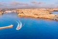 Tugboat sails to meet liner or cargo ship in port of Malta Valletta. Aerial view