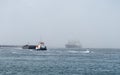 Tugboat towing a barge on rough sea in the fog