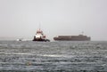 Tugboat towing a barge on rough sea in the fog