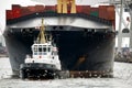 Tugboat towing freighter in harbor Royalty Free Stock Photo