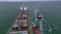 Tugboats pull a big ship with a helipad by sea. Look at the scrunch. Aerial drone shot boat speed sailing in blue sea