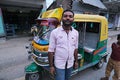 A tuk tuk driver poses in front of his vehicle in Kumrokhali, India