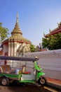 Tuk-tuk taxi in front of the ornate gate of Temple of the Reclining Buddha, Bangkok, Thailand