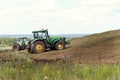 Tula region, Russia, 08.05.2022 Two tractors at the silo compact freshly cut heavy corn with wheels, fermented corn will