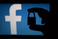 Tula, Russia - August 28, 2018: Facebook security issues. Silhouette of a hand holding a padlock infront .